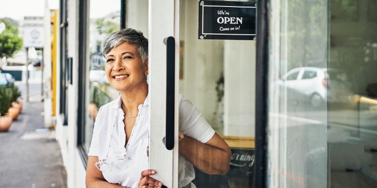 A woman leans out of an open business door.