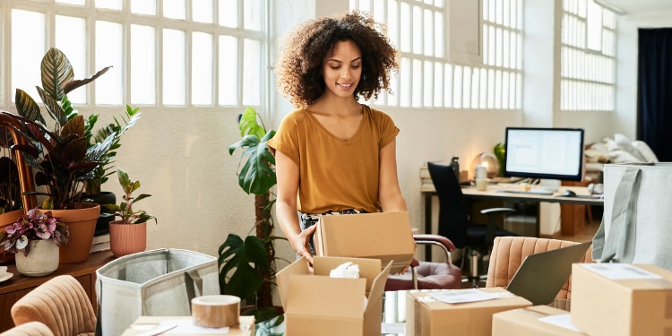 A woman stands in an office opening boxes.