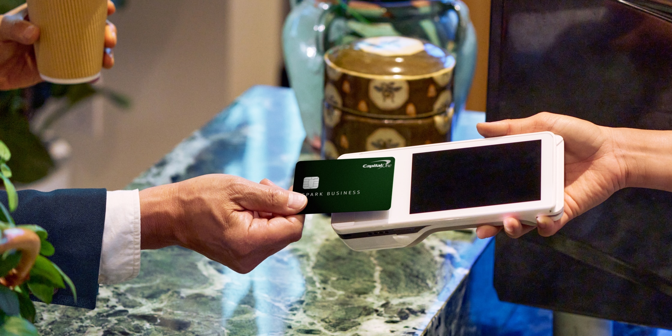 A person taps their green Capital One Spark business card against a card reader.