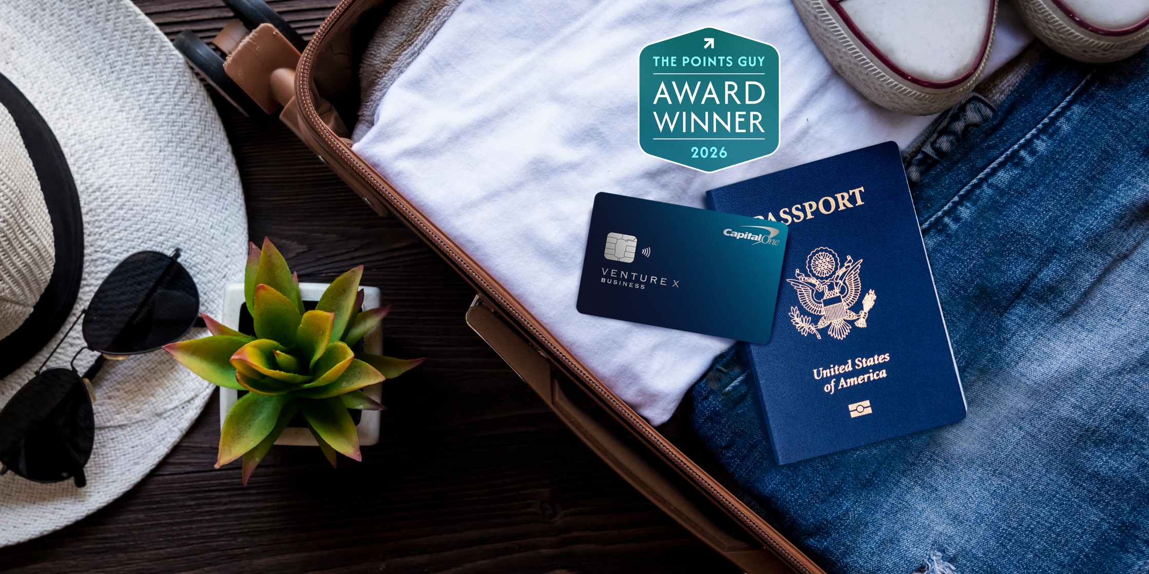 A Venture X Business card and a passport sit atop luggage.