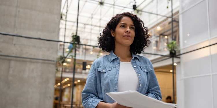 A businesswoman holding business plan documents in an office space, ready to share with others.