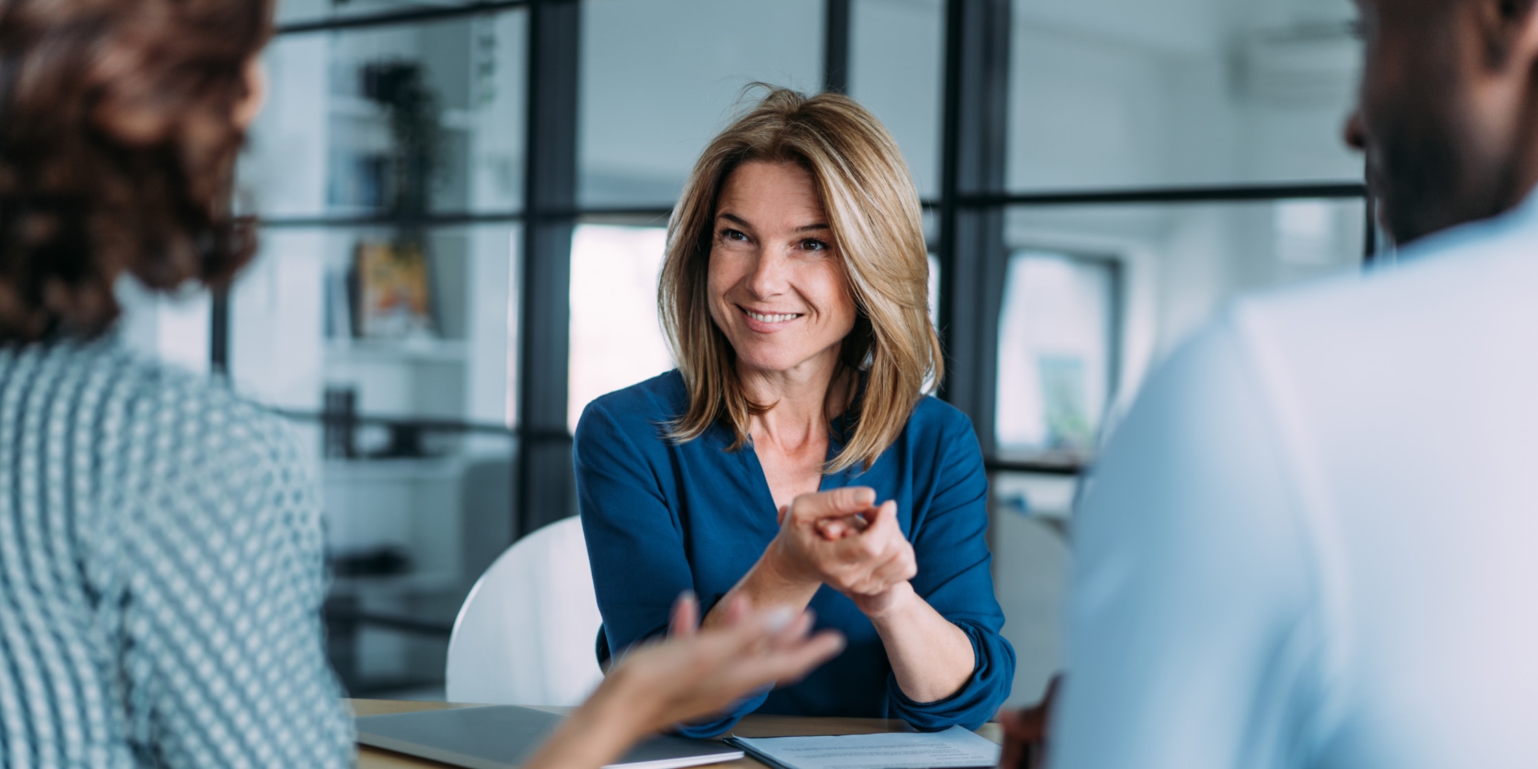 Business owner sitting at a table and having a conversation with two others.