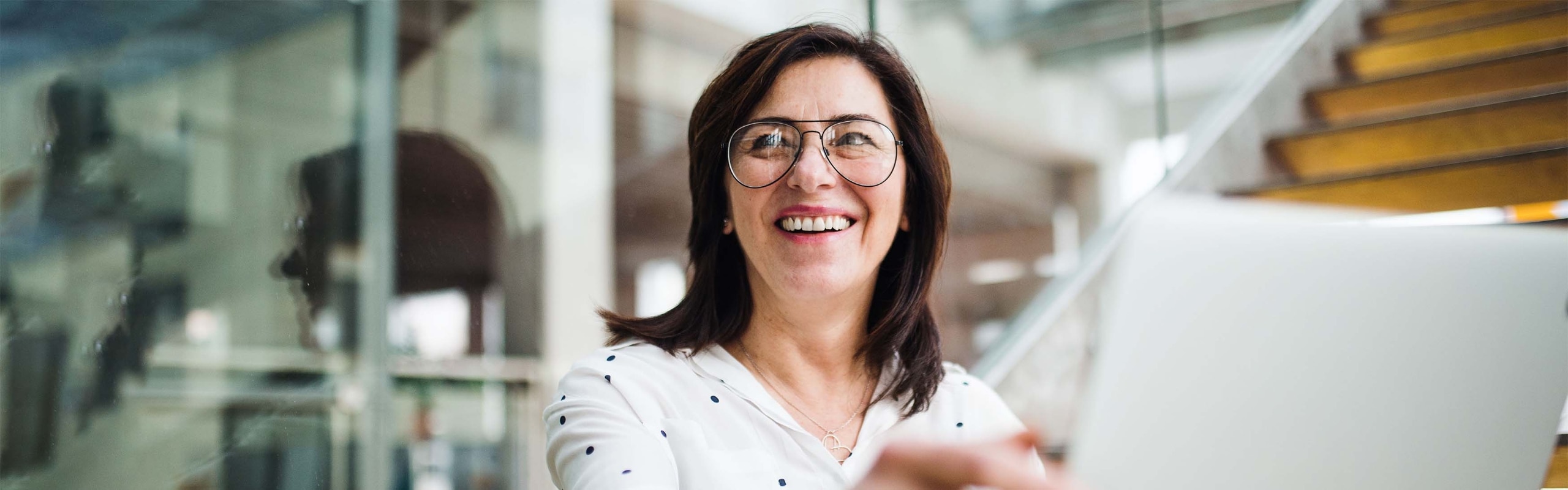 Woman with glasses and polka dot shirt smiling