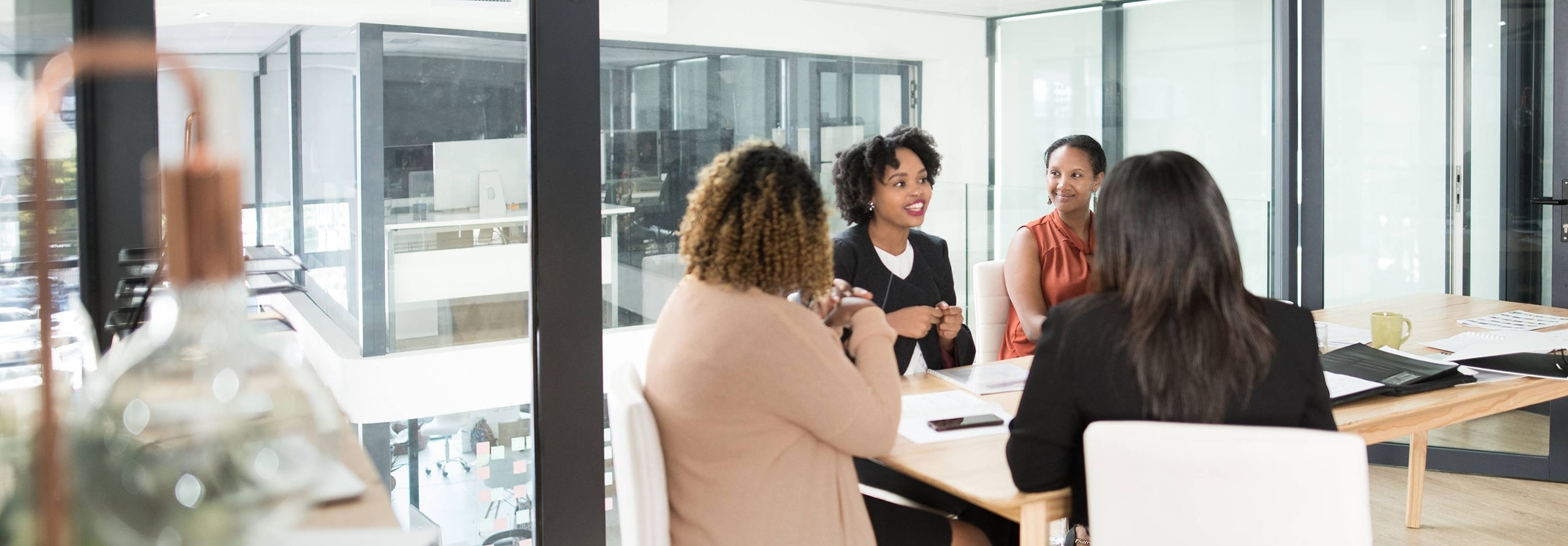 A group of women sit and converse at a conference table