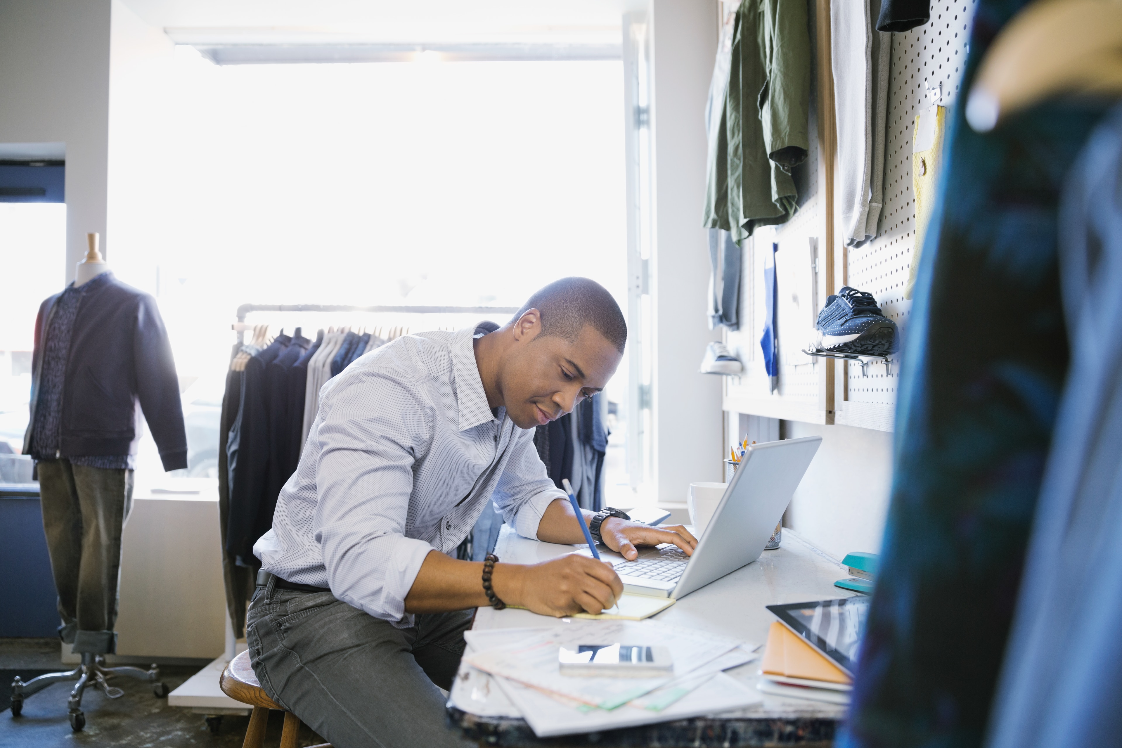 Man taking notes next to a laptop