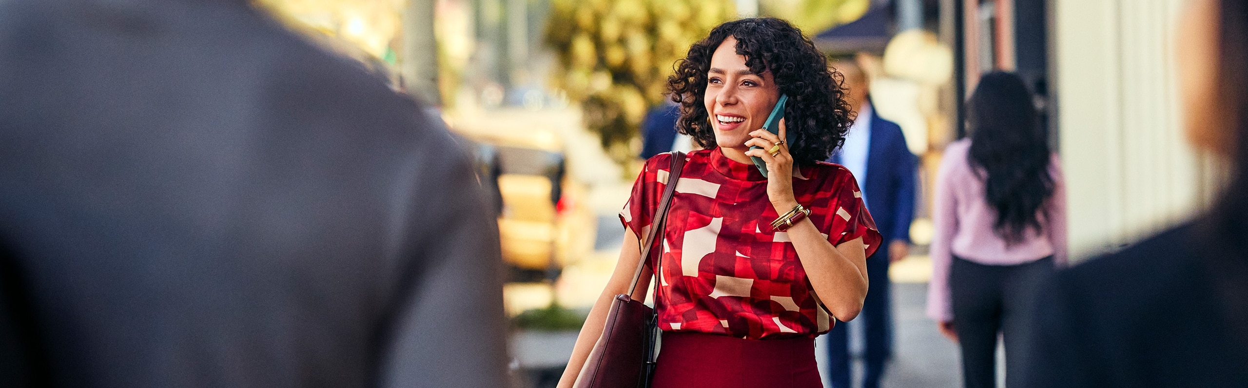 Woman in a red shirt smiling and on the phone