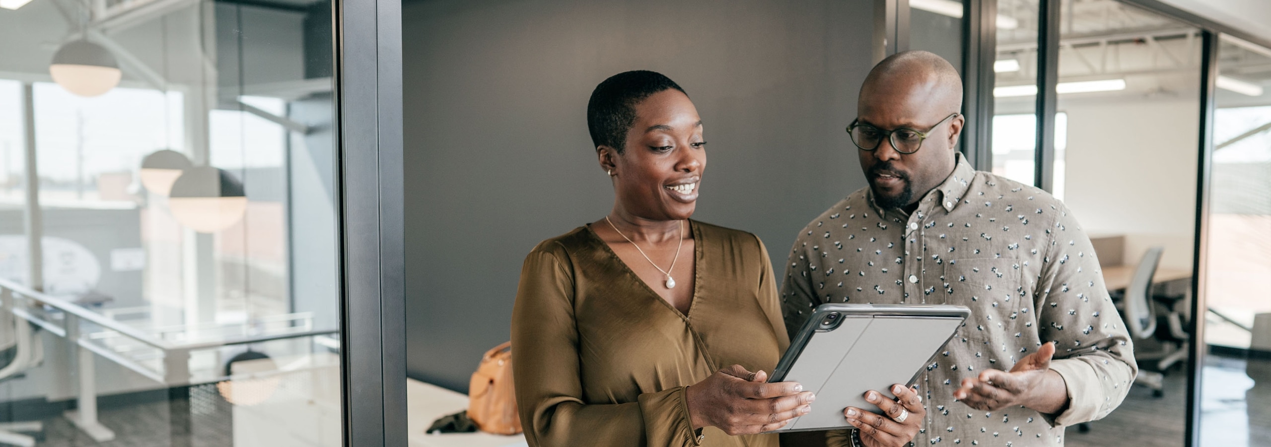 A man and a woman look at a tablet together in an office