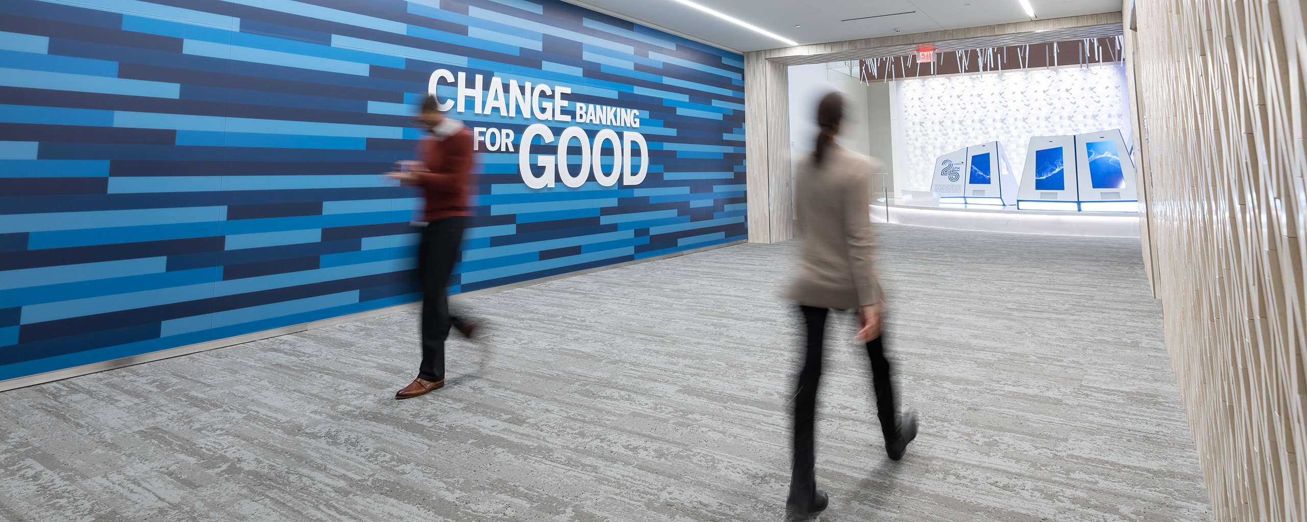 Capital One associates walking in front of Changing Banking for Good wall art