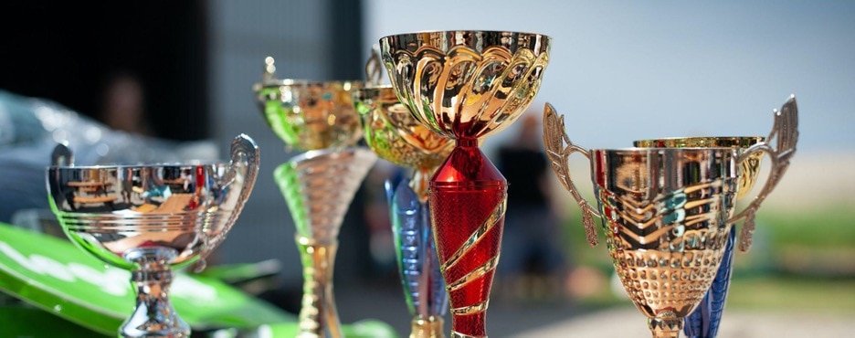 Six shiny trophies of various sizes and styles.
