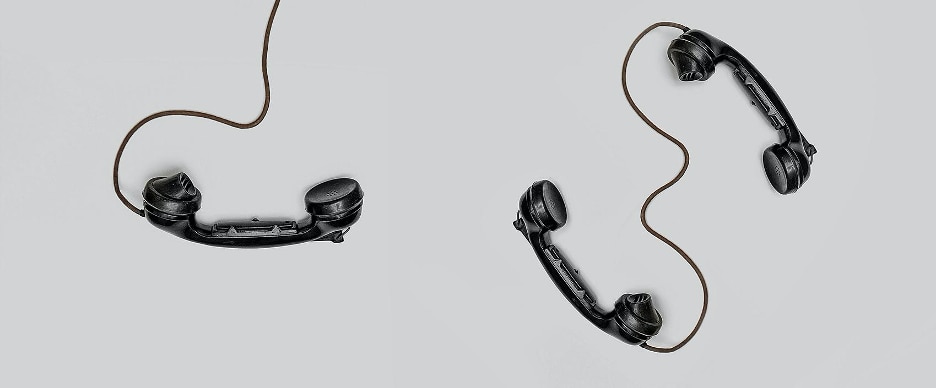 black telephones with wires laid on grey background