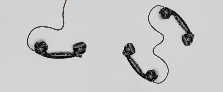 black telephones with wires laid on grey background