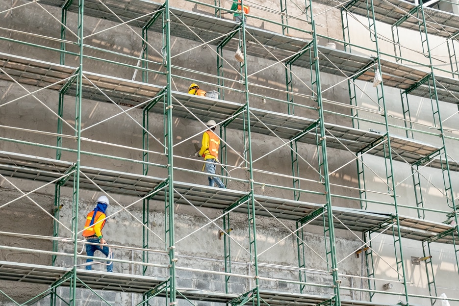construction workers wearing bright orange vests scaling a building site