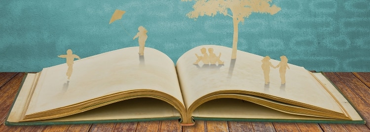 book opened on wooden table. emerging from book are beige silhouette of young children sitting reading a book under a tree. there is a teal backdrop to the image