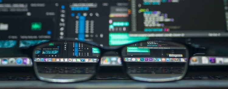 Artisitic shot of a laptop screen with many open windows and applications as shot through a pair of black rimmed glasses
