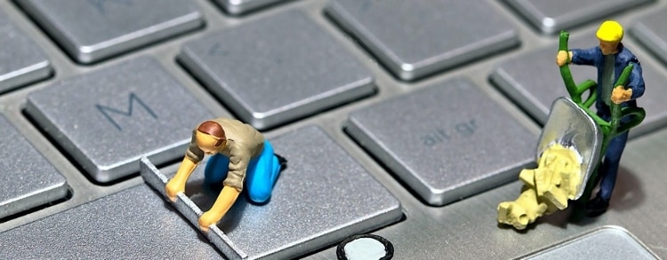 figurines dressed as construction workers, sitting on computer keyboard keys