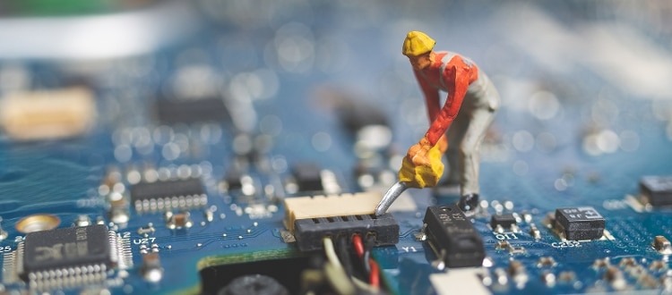 figurine of male construction worker wearing yellow hat, standing on a blue computer switchboard