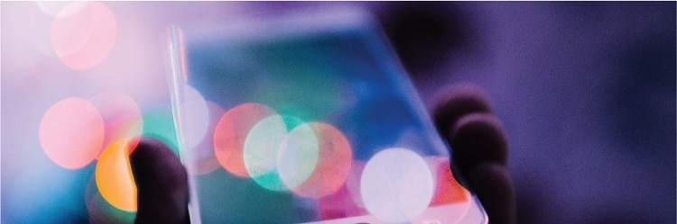 blurred shot of hand holding phone, with pink, white, and orange circles overlayed on it.