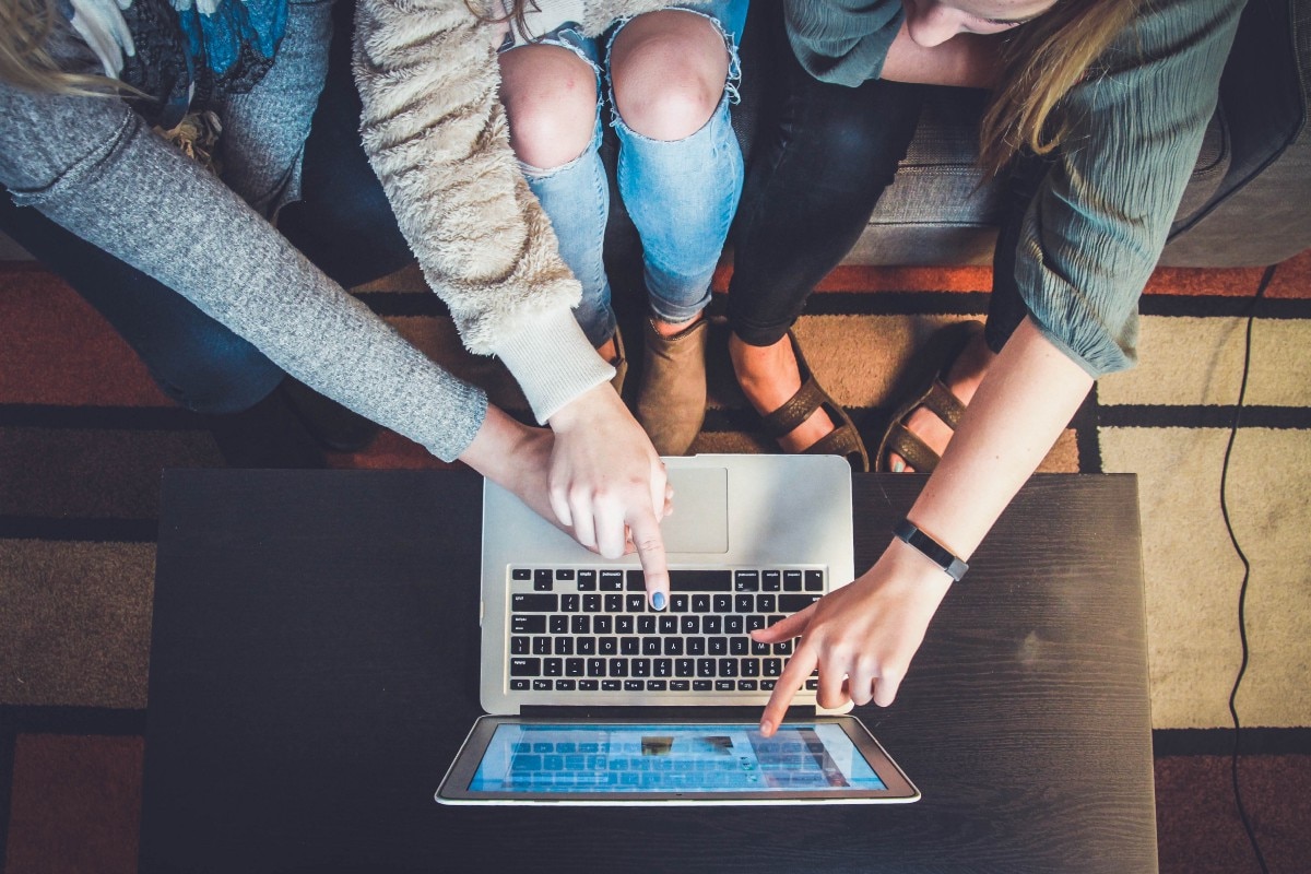 2 hands pointing to open silver laptop computer screen