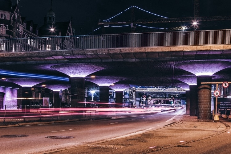 highway underpass with columns illuminated in purple lights