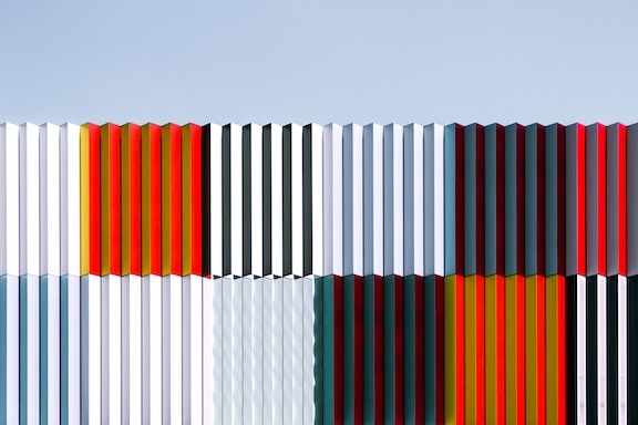 stack of shipping containers in grey, white, black, and rusty orange