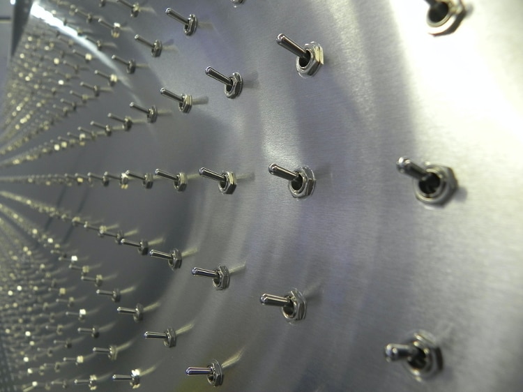 fisheye lens view of a shiny metal wall covered in simple metal on/off switches