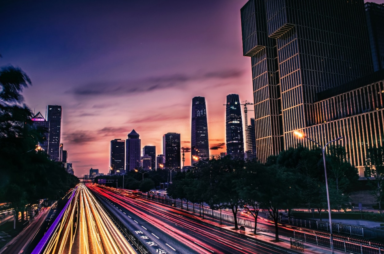 dark city skyline with skycrapers with pink, orange, and blue sunset in background
