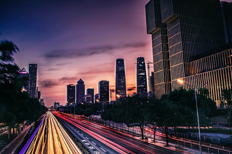 dark city skyline with skycrapers with pink, orange, and blue sunset in background