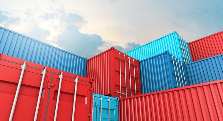red and blue shipping containers stacked towards a cloudy sky