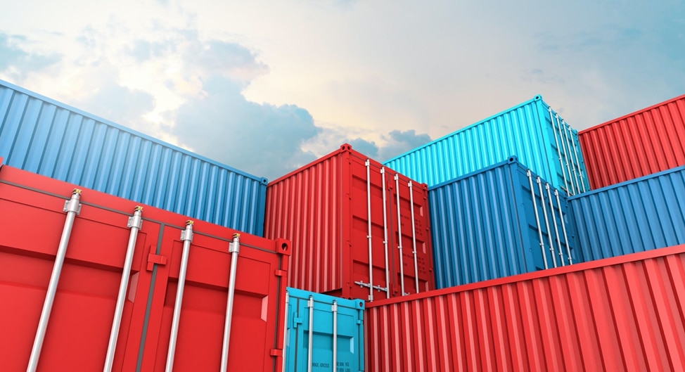red and blue shipping containers stacked towards a cloudy sky