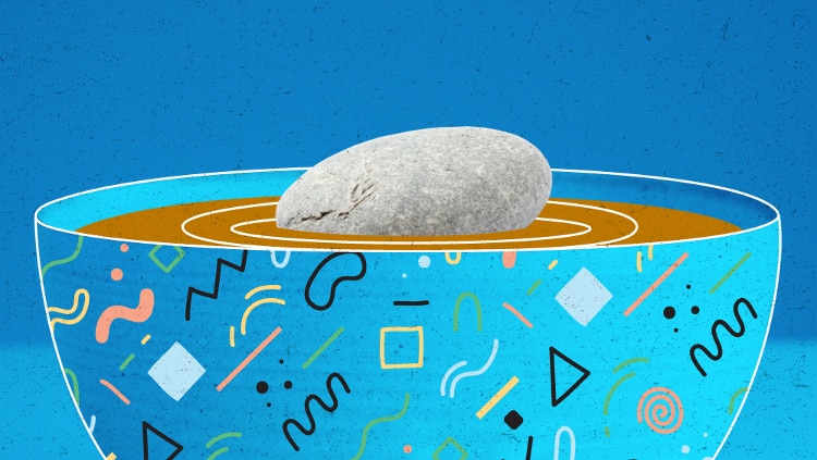 dark-to-light blue gradient with bowl in center of image outlined in white. bowl has abstract pink, blue, yellow, green, and black designs scattered across the surface and is filled with brown liquid. there is a large oval-shaped grey stone in middle of bowl.