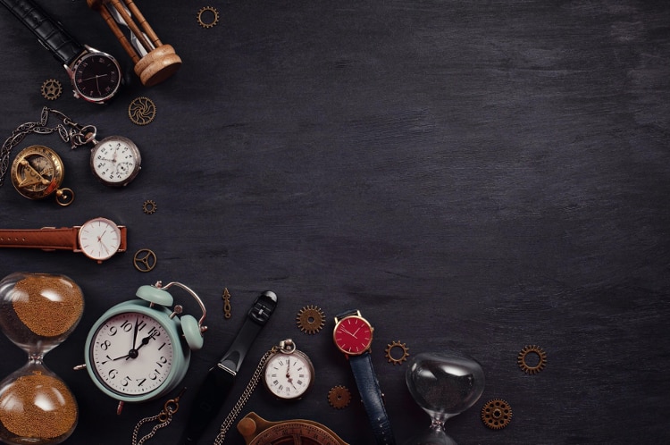 pocket watches and clocks laid out in a wave on a black table