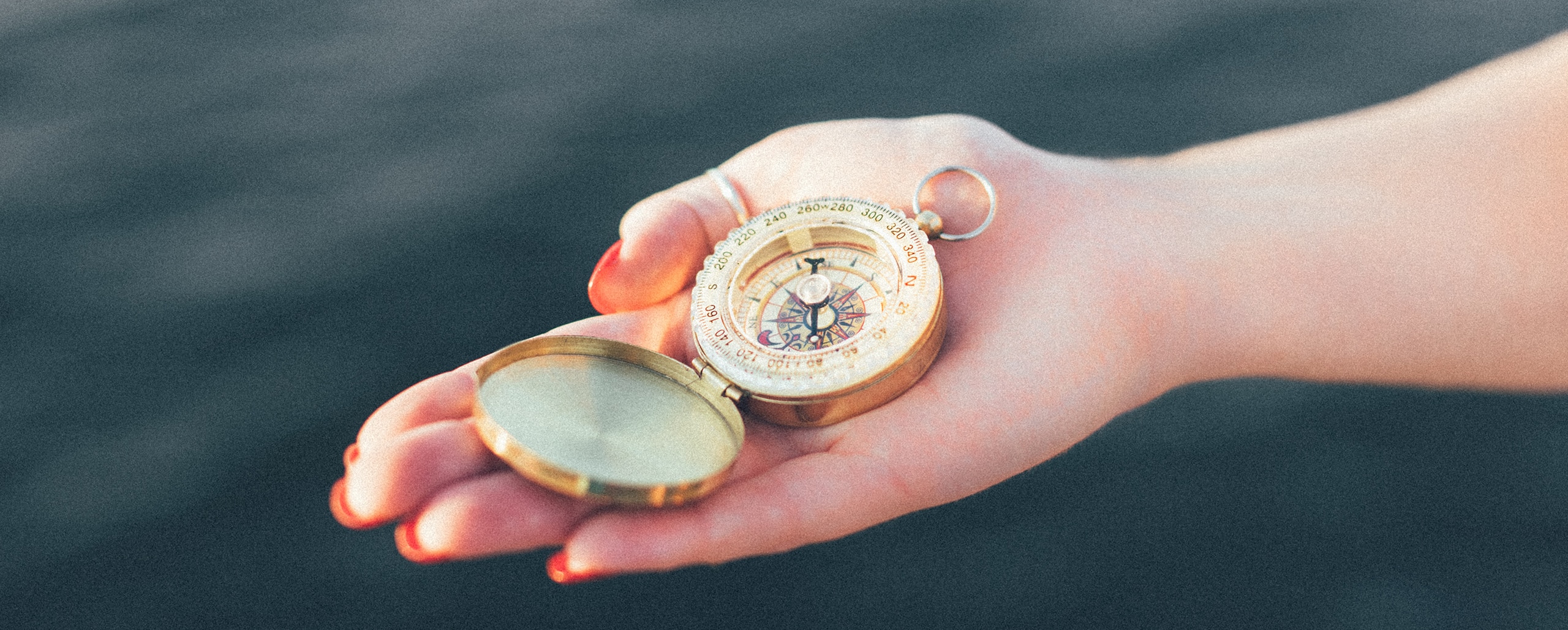 hand holding a gold compass