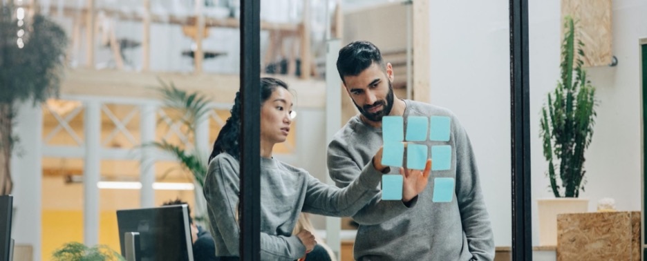 Tech associates mapping out strategy process on glass wall