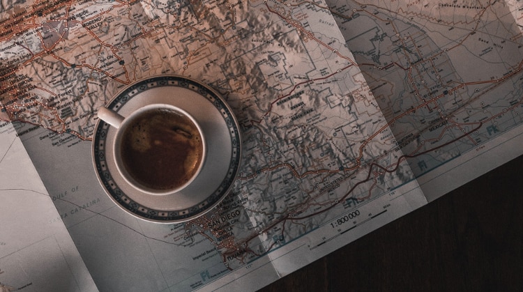 Cup of coffee sitting in a saucer on a paper map