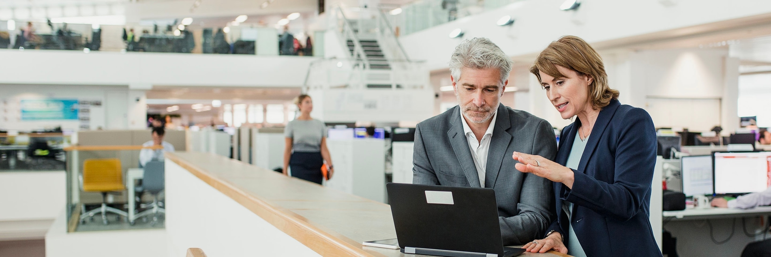 photo of 2 people looking at a laptop, discussing business
